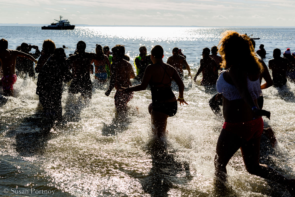 Stunning Silhouette Photos Guaranteed to Inspire Your Travels-People running into ice cold water at the Polar Bear Plunge on Coney Island in New York City.