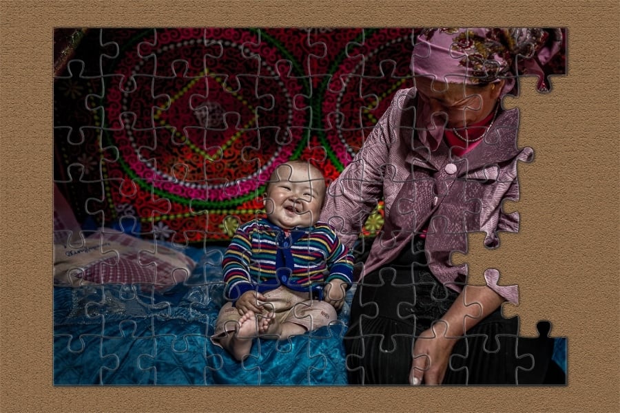 Puzzle - Mongolian baby laughing on a bed with his grandmother